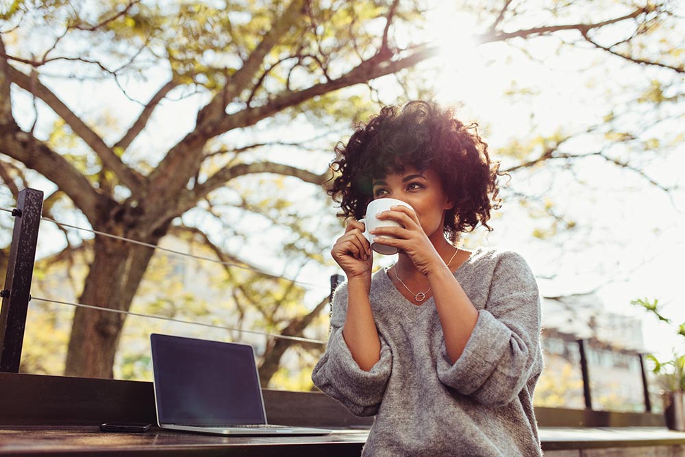 curly black woman drinking from a cup