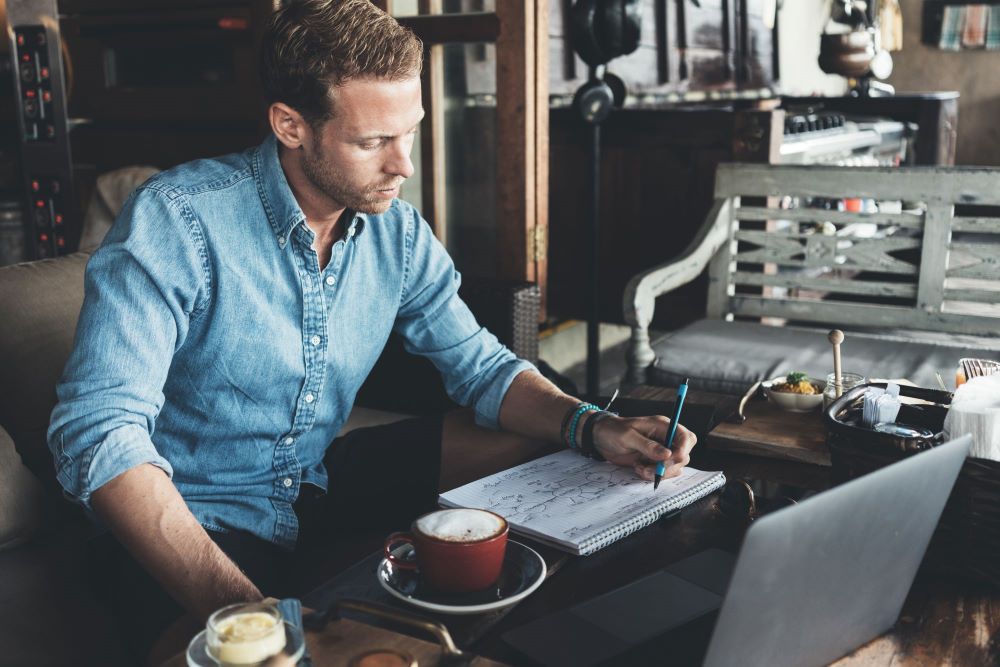 man at coffee shop participating in an online coach training program
