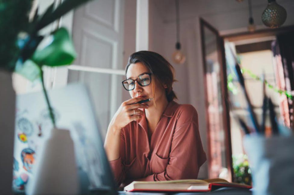 Woman holding a pen looking pensive

