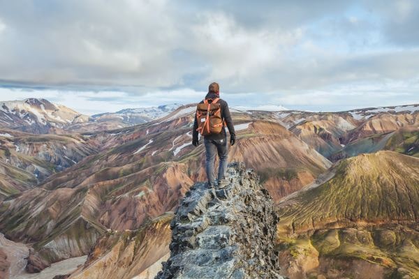 hiker standing on peak, looking out at mountain range