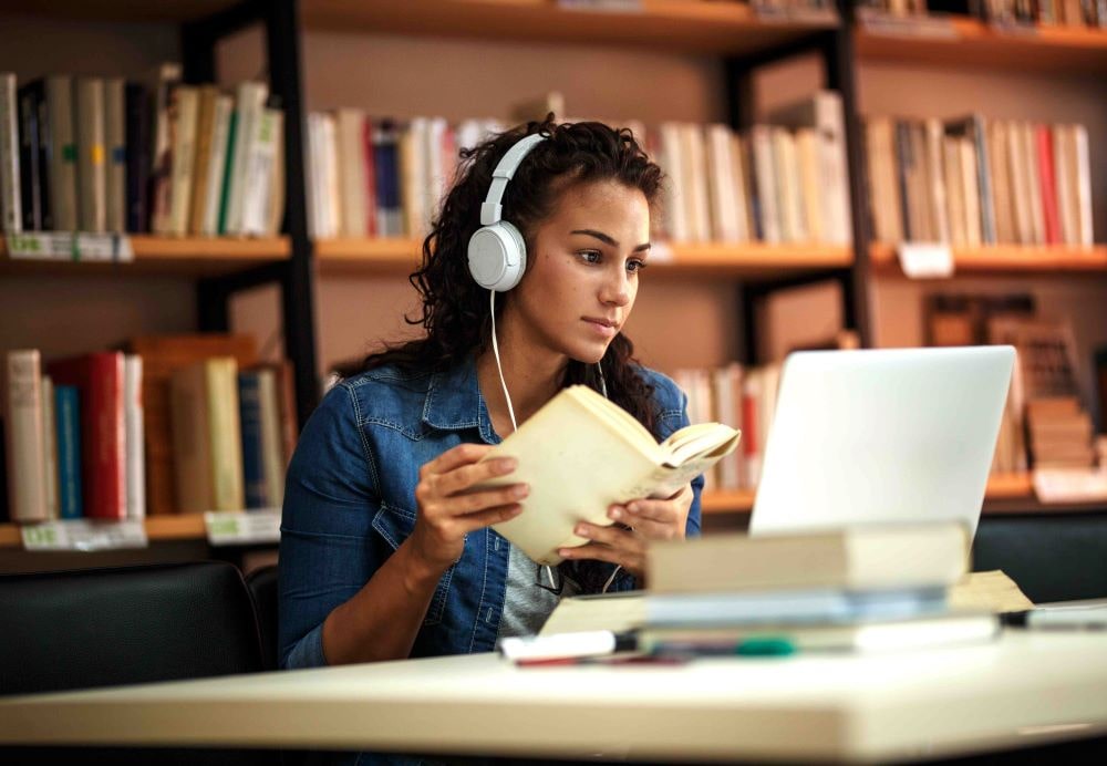Woman in library studying on her laptop