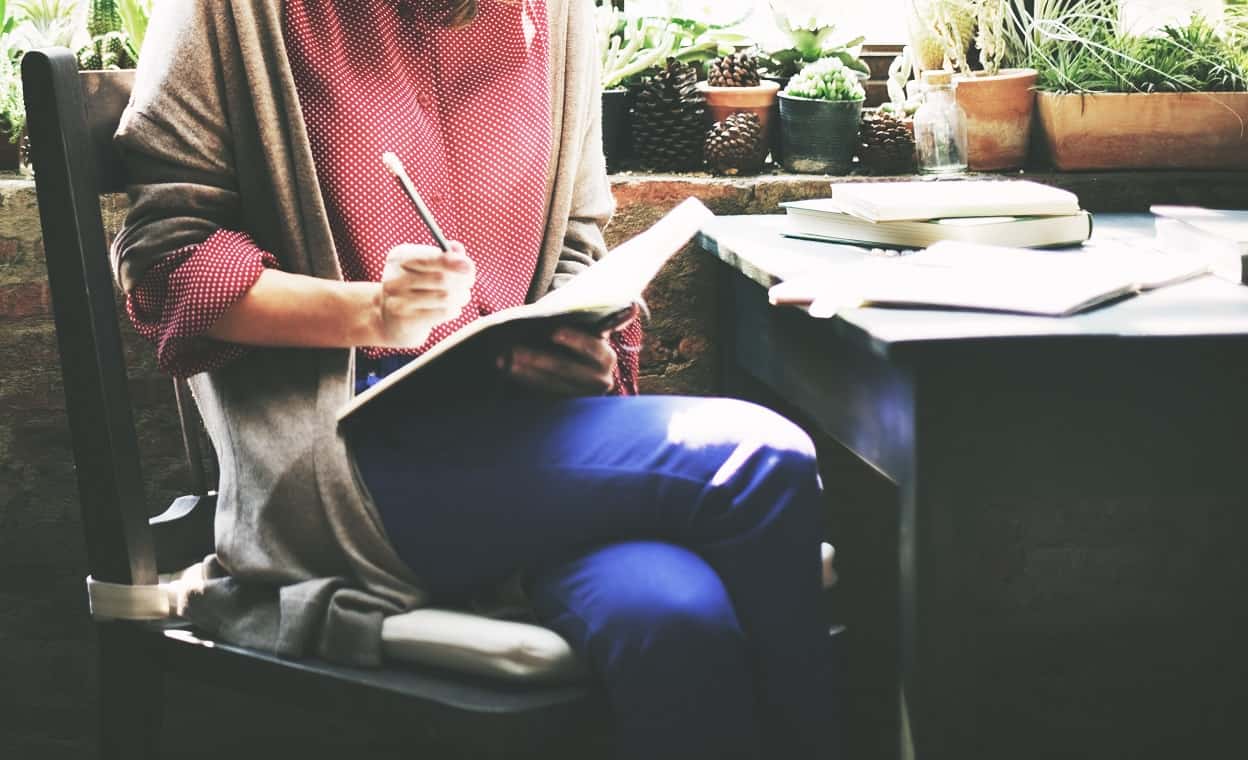 Woman sitting at a table, books spread out across it studying for a test