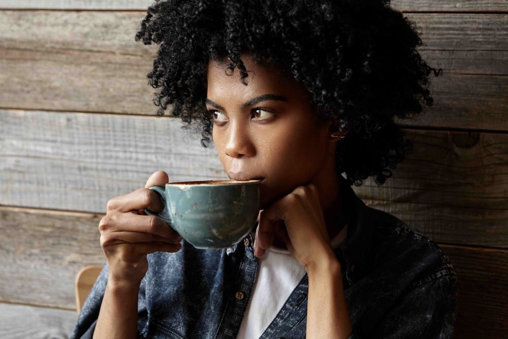 Woman drinking a cup of coffee, looking thoughtfully into the distance