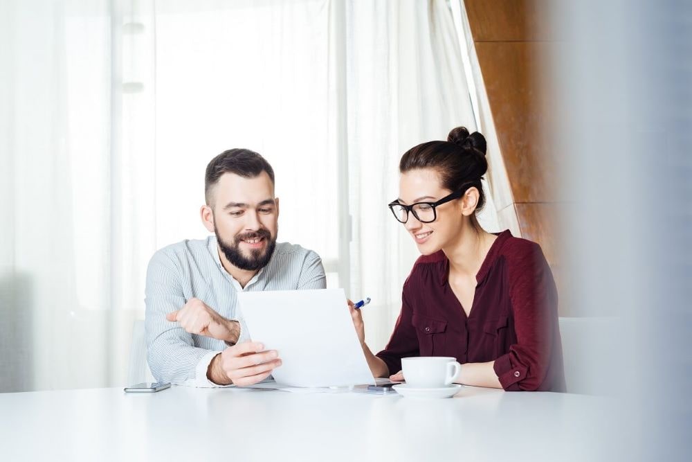 Man and a woman sitting at a table, looking at a list