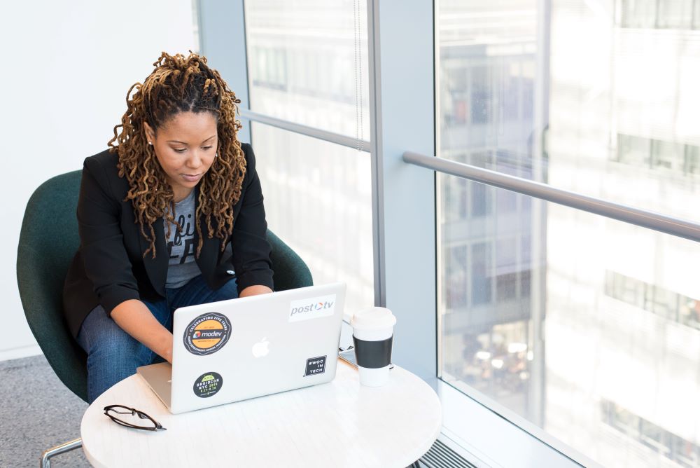 Woman sitting by window working on her laptop